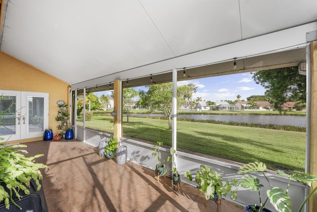 unfurnished sunroom featuring lofted ceiling, plenty of natural light, and a water view