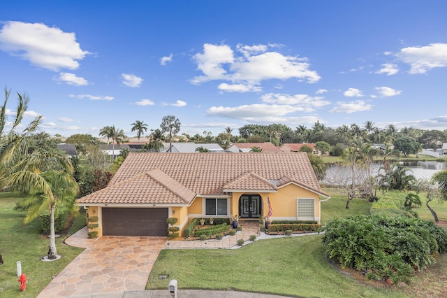 mediterranean / spanish house featuring a garage, a front yard, and a water view