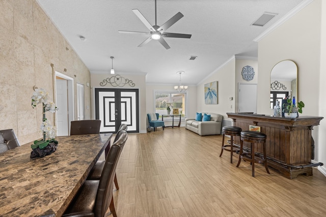 dining area with ornamental molding, indoor bar, ceiling fan with notable chandelier, and a textured ceiling