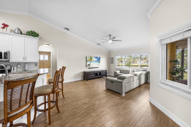 living room featuring ceiling fan, ornamental molding, lofted ceiling, and hardwood / wood-style floors