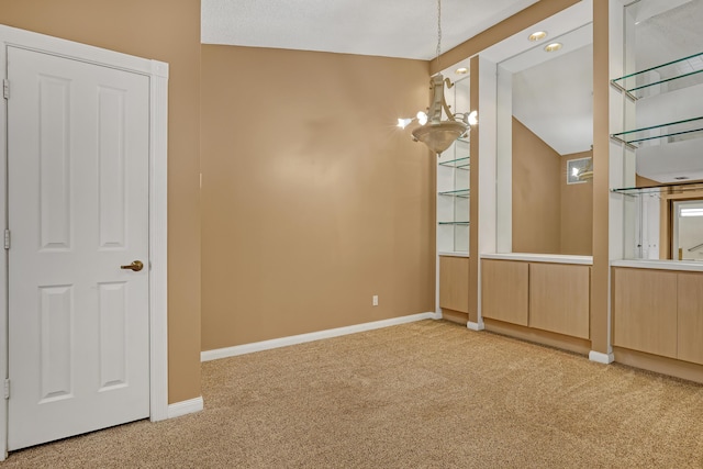 carpeted empty room with vaulted ceiling and a chandelier