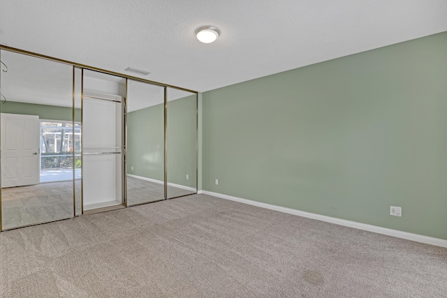 unfurnished bedroom with light carpet, a textured ceiling, and a closet