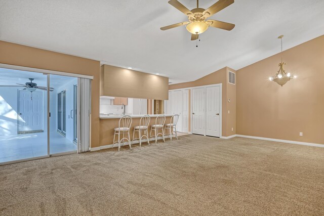 unfurnished living room featuring vaulted ceiling, ceiling fan, and carpet