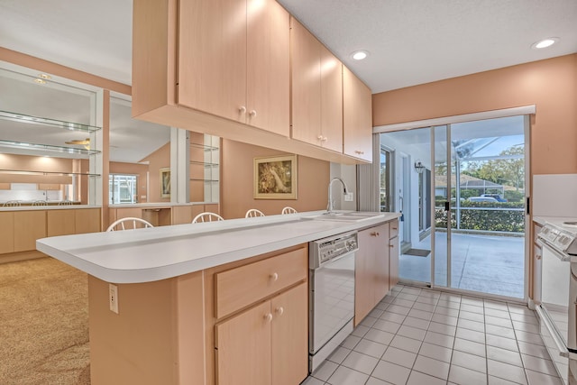 kitchen with light brown cabinetry, sink, light tile patterned floors, kitchen peninsula, and white appliances