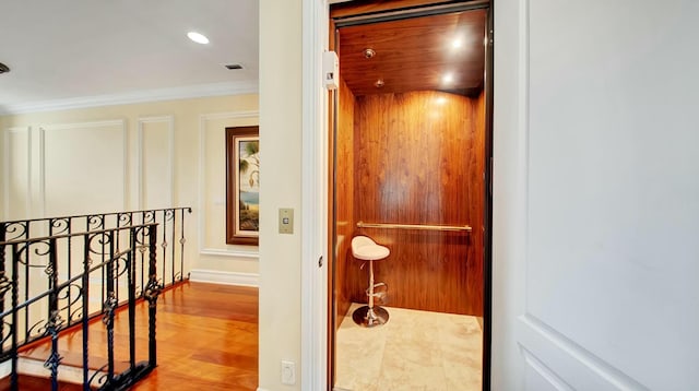 corridor featuring recessed lighting, visible vents, ornamental molding, elevator, and an upstairs landing