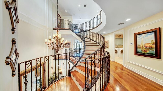 stairs featuring washing machine and clothes dryer, visible vents, a high ceiling, baseboards, and hardwood / wood-style flooring