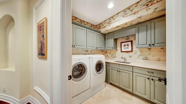 laundry area featuring separate washer and dryer, a sink, and cabinet space