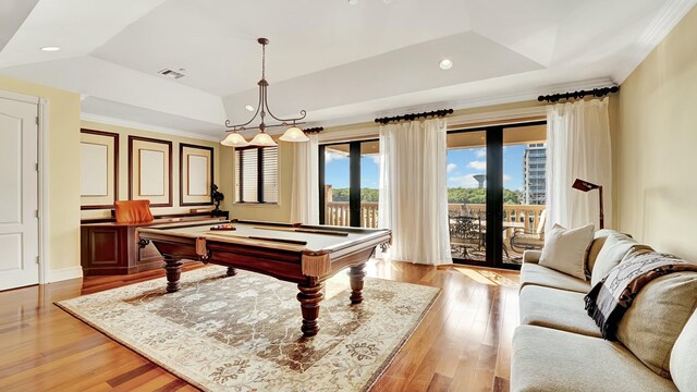 game room featuring visible vents, light wood-style flooring, ornamental molding, pool table, and a tray ceiling