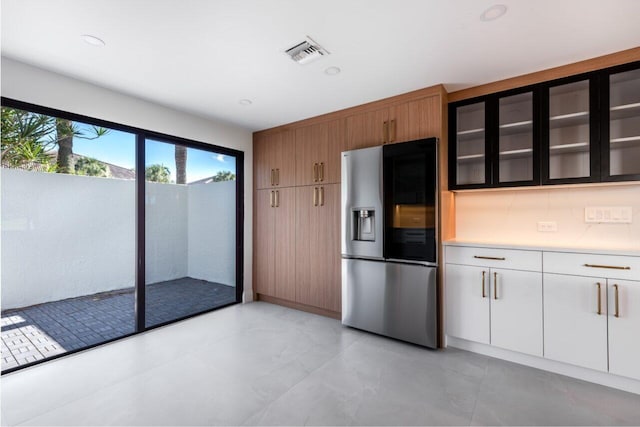 kitchen featuring white cabinets, backsplash, and stainless steel fridge with ice dispenser