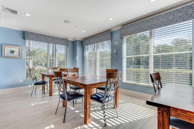 dining space with crown molding and light hardwood / wood-style floors