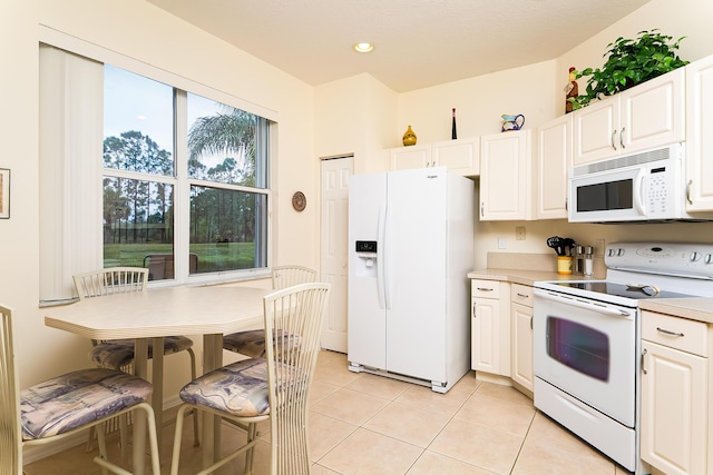 kitchen featuring light tile patterned floors, white appliances, and white cabinets