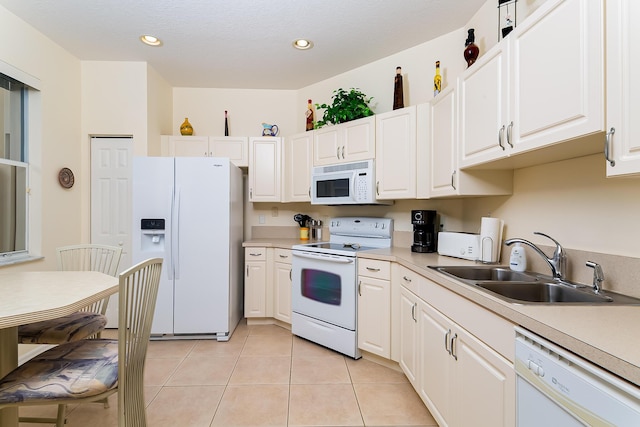 kitchen featuring sink, white appliances, light tile patterned floors, and white cabinets