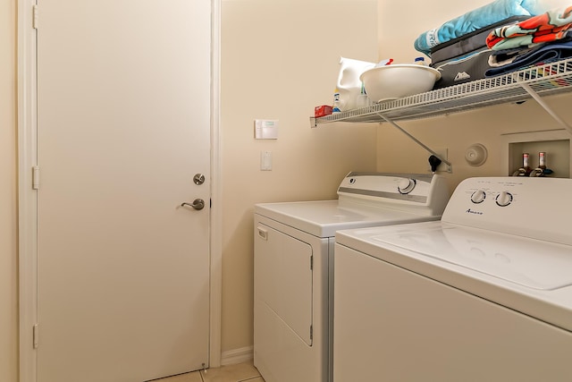 clothes washing area with washer and dryer and light tile patterned floors