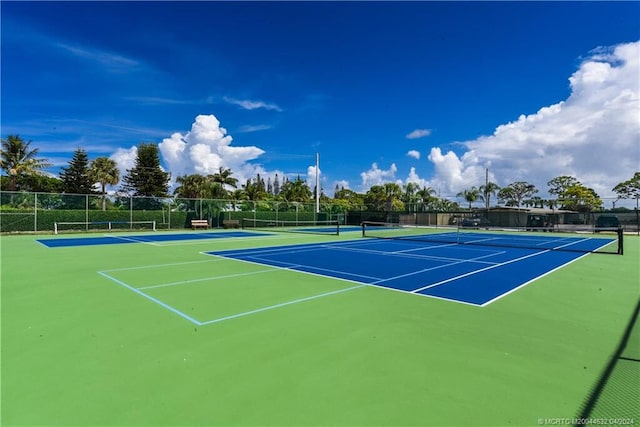 view of tennis court featuring community basketball court and fence