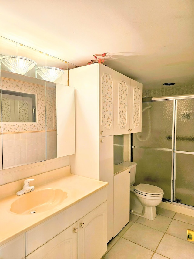 bathroom featuring tile patterned flooring, toilet, vanity, and a stall shower