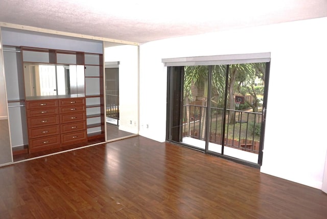 empty room featuring a textured ceiling, dark wood-type flooring, and a wealth of natural light