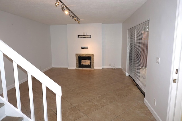 unfurnished living room with tile patterned floors, a textured ceiling, and rail lighting