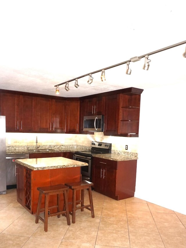 kitchen with a kitchen breakfast bar, appliances with stainless steel finishes, a center island, and light stone countertops