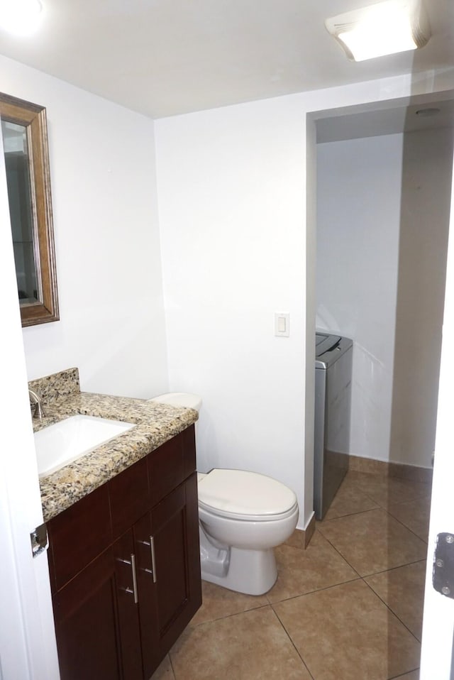 bathroom with toilet, washer and dryer, tile patterned floors, and vanity