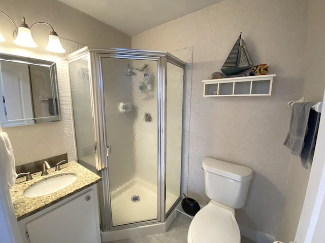 bathroom featuring toilet, a shower with shower door, and vanity