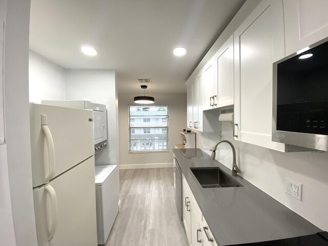 kitchen featuring kitchen peninsula, appliances with stainless steel finishes, white cabinets, light hardwood / wood-style flooring, and sink