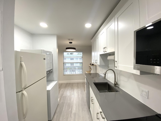 kitchen with light hardwood / wood-style floors, sink, white cabinetry, hanging light fixtures, and stainless steel appliances