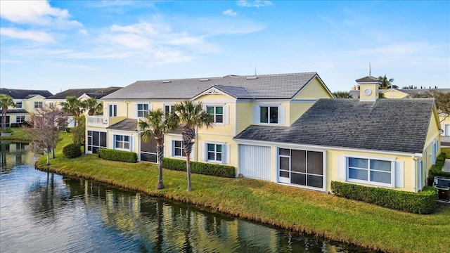 exterior space with a water view, a balcony, and a lawn