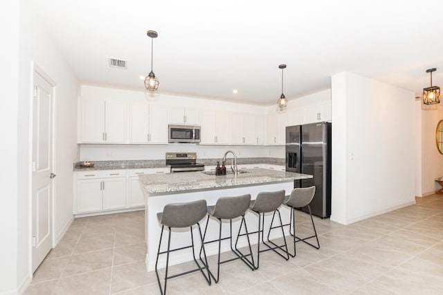 kitchen featuring sink, light stone counters, an island with sink, stainless steel appliances, and white cabinets