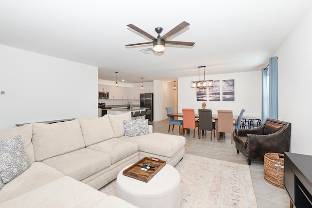 tiled living room featuring sink and ceiling fan with notable chandelier