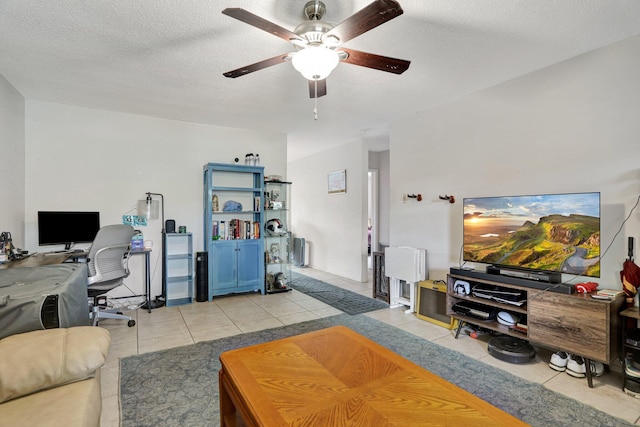 living room featuring light tile patterned flooring, ceiling fan, and a textured ceiling