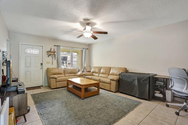 living room with light tile patterned flooring, ceiling fan, and a textured ceiling