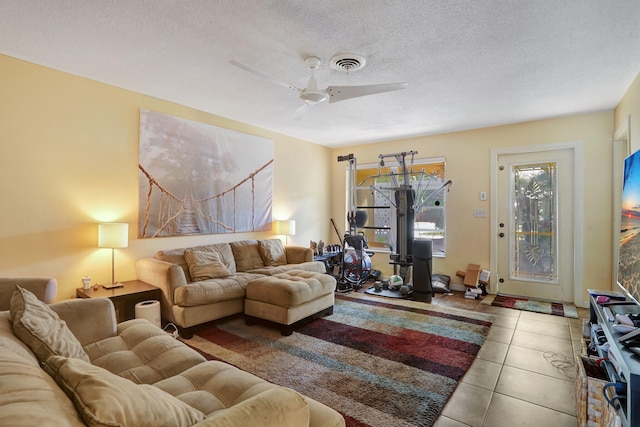 living room featuring ceiling fan, a textured ceiling, and light tile patterned flooring