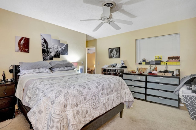 bedroom featuring a textured ceiling, light colored carpet, and ceiling fan