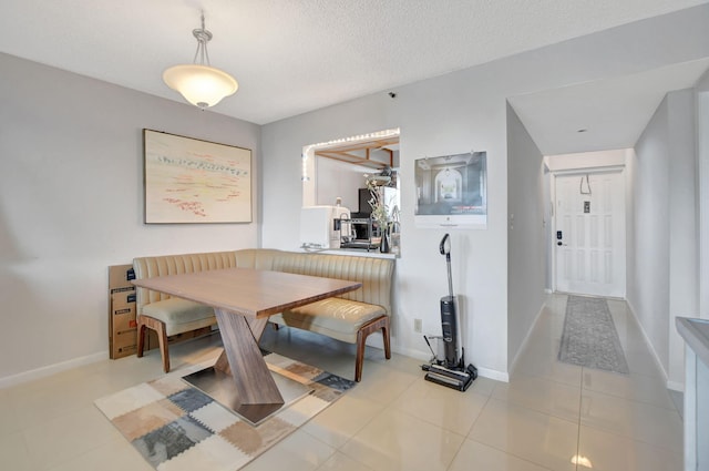 tiled dining space with a textured ceiling and breakfast area