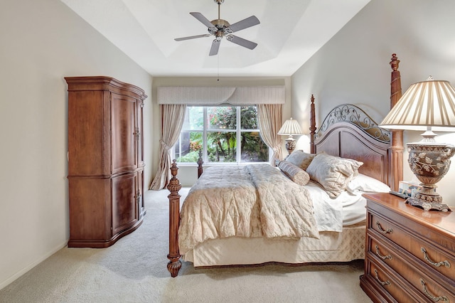 carpeted bedroom featuring ceiling fan and a tray ceiling