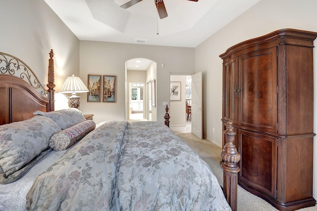 carpeted bedroom with ceiling fan and a tray ceiling