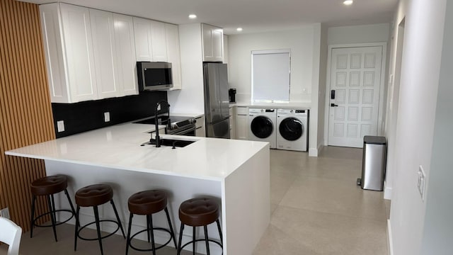 kitchen with tasteful backsplash, a breakfast bar, kitchen peninsula, stainless steel appliances, and white cabinets