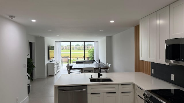 kitchen featuring appliances with stainless steel finishes, white cabinetry, decorative backsplash, sink, and kitchen peninsula