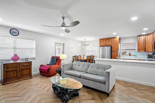 living room featuring ceiling fan with notable chandelier and light parquet floors