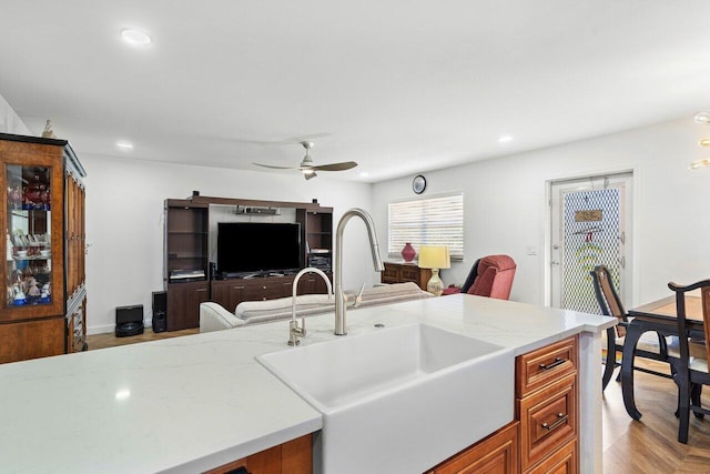 kitchen with ceiling fan, sink, and light stone countertops