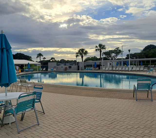 pool at dusk featuring a patio area