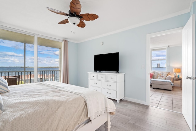 bedroom featuring crown molding, access to exterior, light wood-type flooring, a water view, and ceiling fan