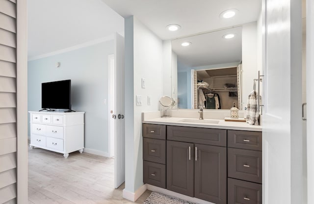 bathroom featuring built in shelves, hardwood / wood-style floors, ornamental molding, and vanity