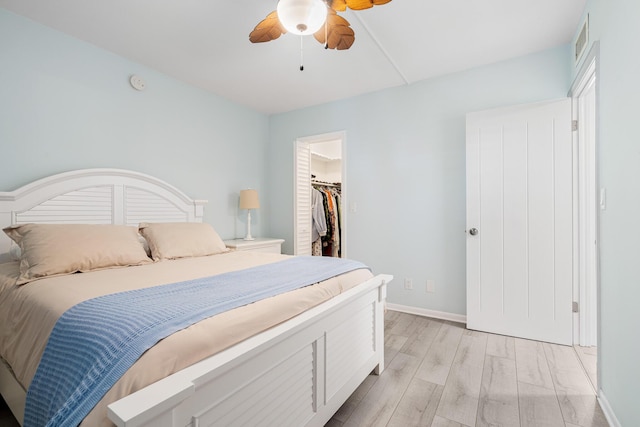 bedroom featuring ceiling fan, light hardwood / wood-style floors, a closet, and a spacious closet