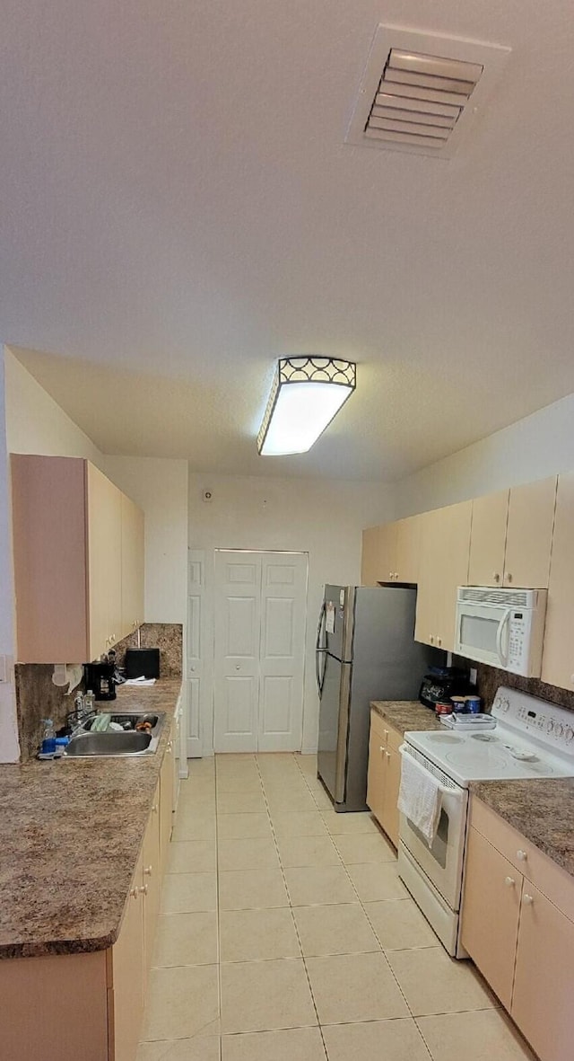 kitchen featuring light tile patterned flooring, sink, white appliances, cream cabinets, and backsplash