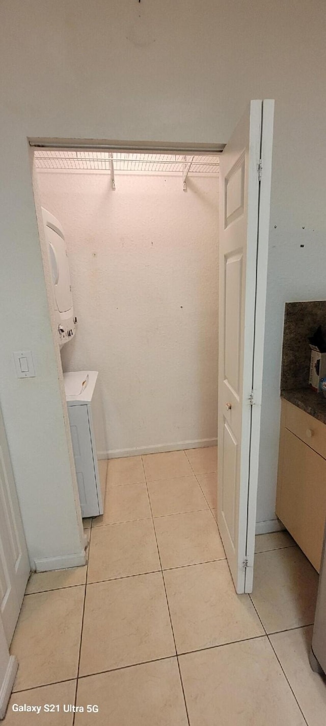 bathroom with stacked washer and clothes dryer and tile patterned flooring