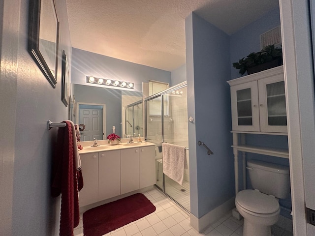 bathroom with tile patterned floors, toilet, a textured ceiling, vanity, and a shower with door