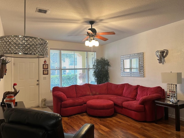 living room with hardwood / wood-style flooring, ceiling fan, and a textured ceiling