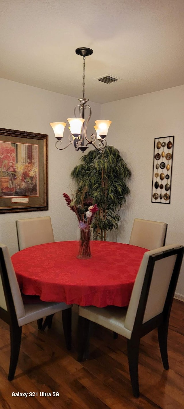 dining space featuring hardwood / wood-style flooring and an inviting chandelier