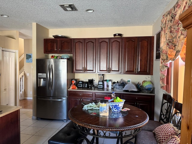 kitchen with stainless steel fridge with ice dispenser, light tile patterned floors, and a textured ceiling